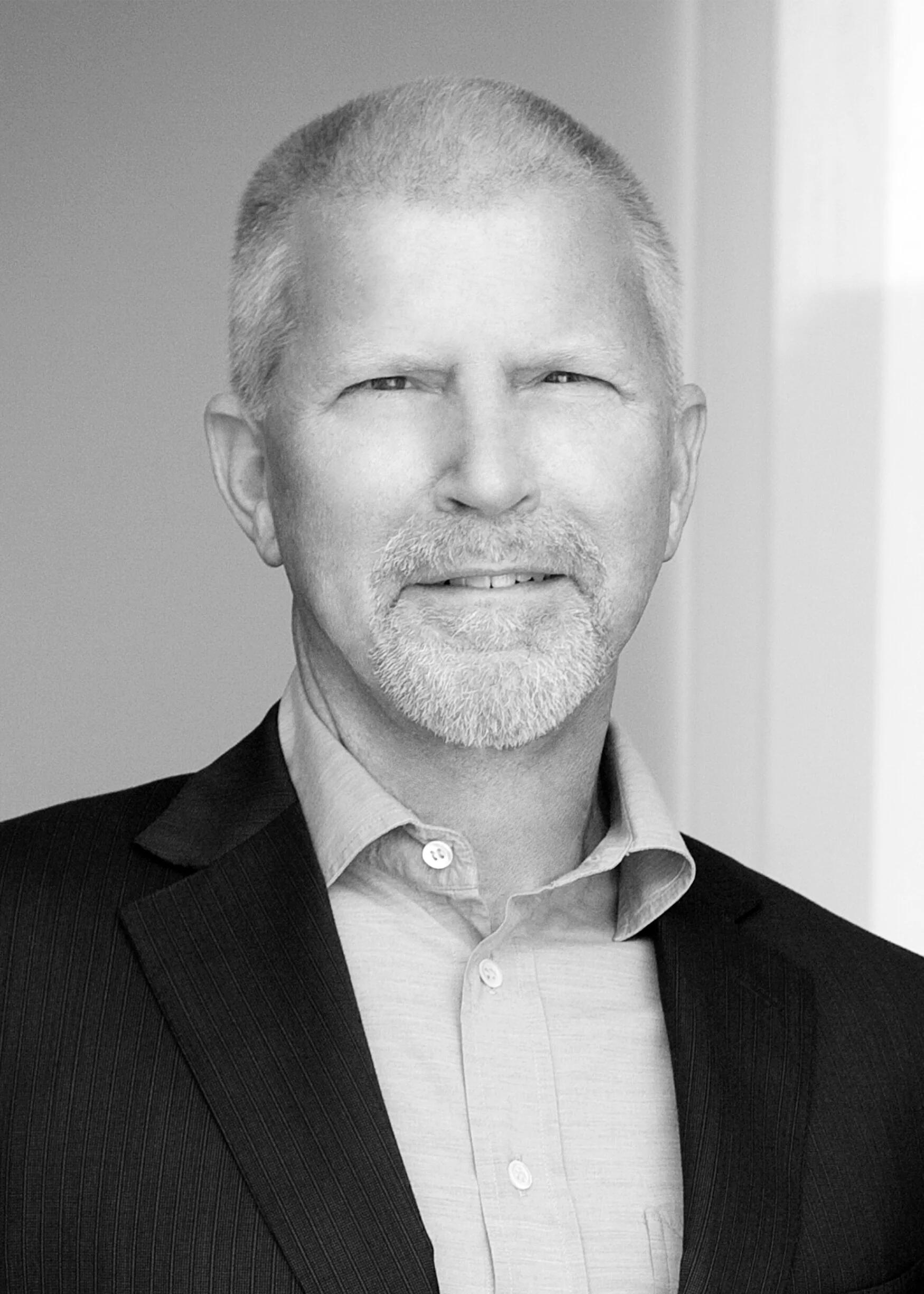 man smiling with a suit and dress shirt in a black and white photo