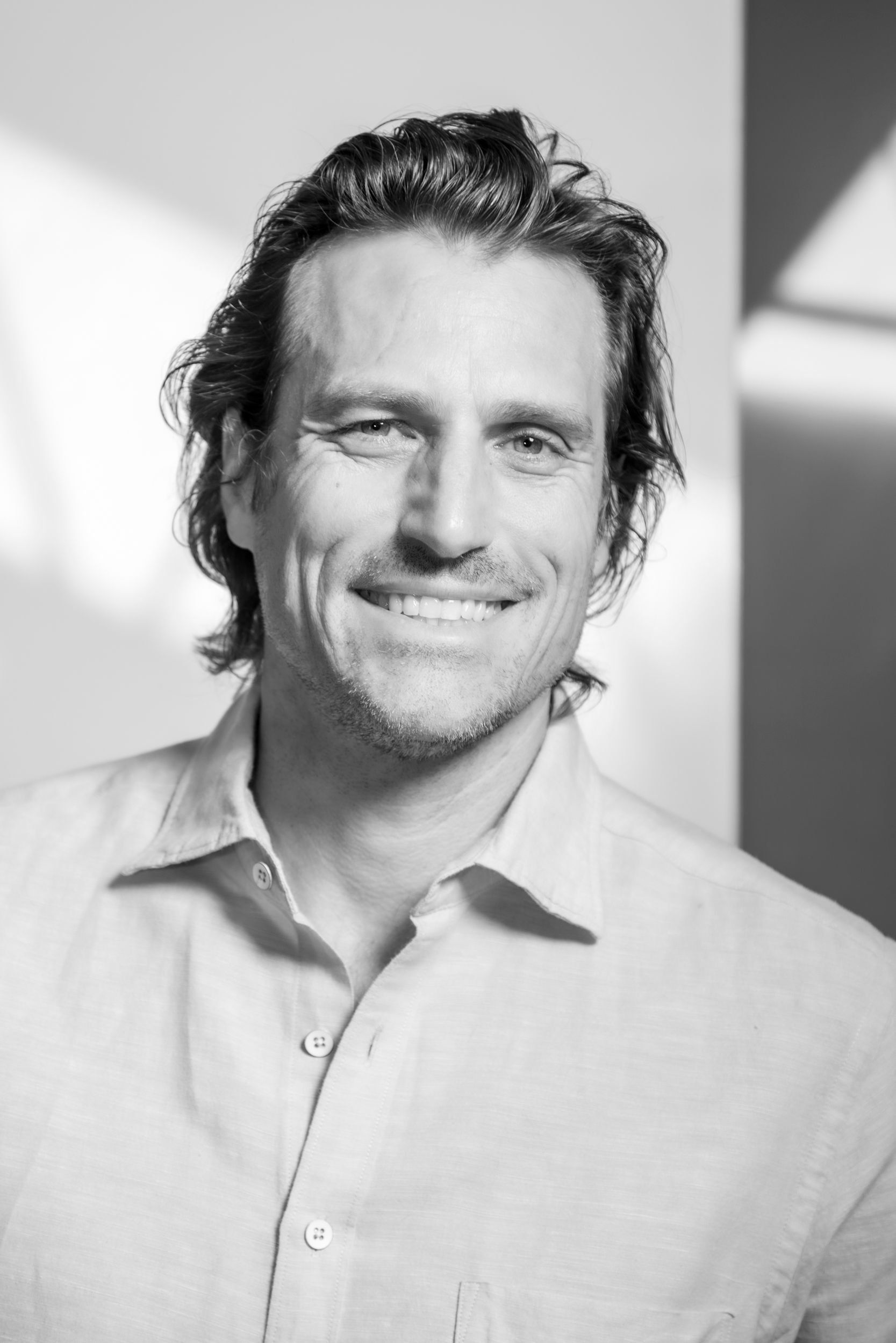 Black and white photograph of Jason Pautz, smiling in sunny light and looking into the camera lens