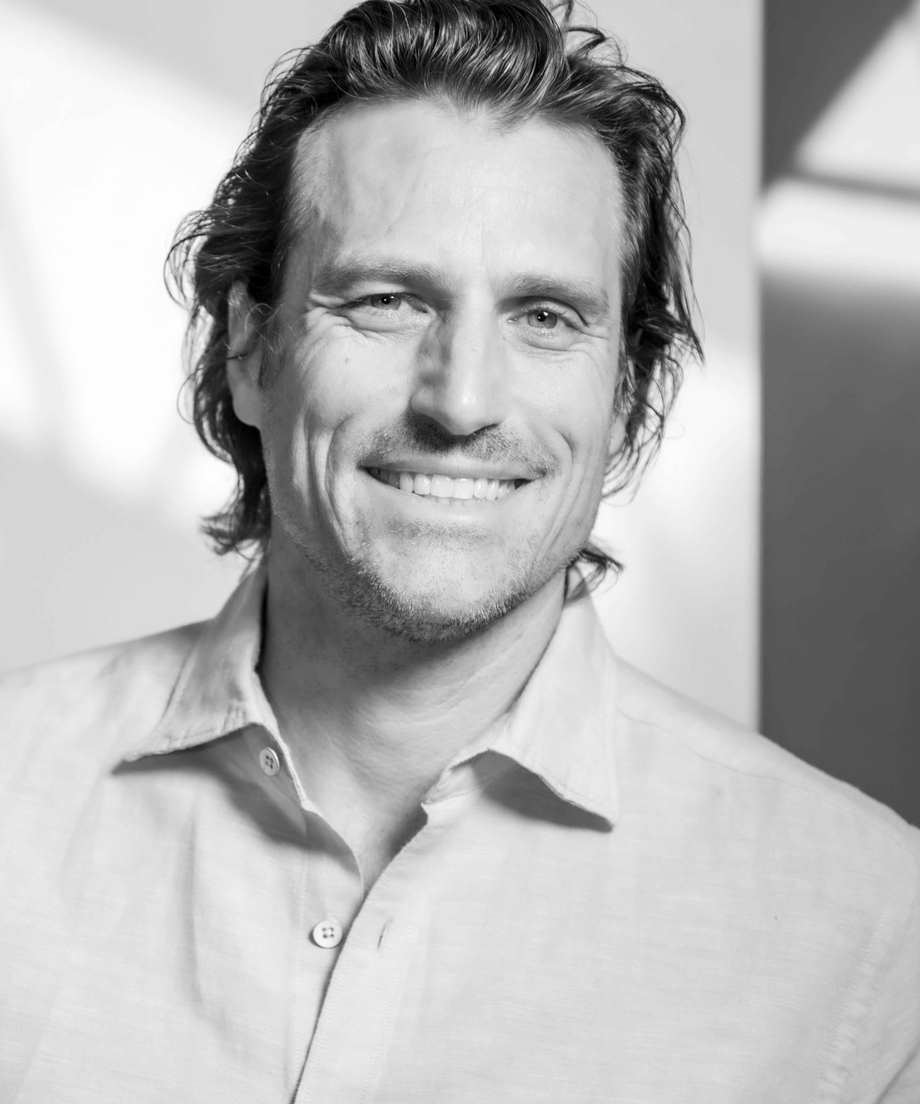 Black and white photograph of Jason Pautz, smiling in sunny light and looking into the camera lens