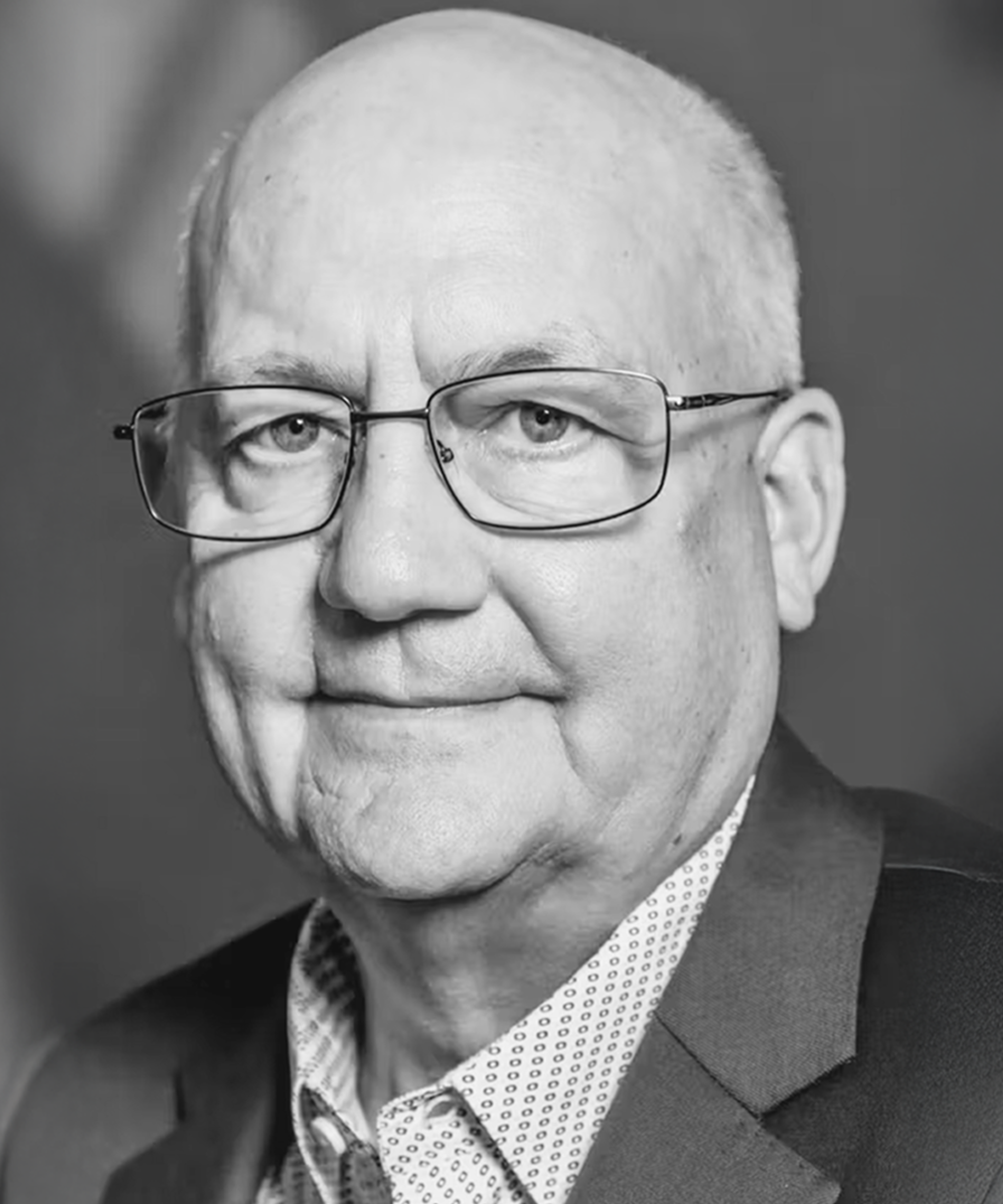 Black and white photograph of Duane Pfannenstiel, wearing thin-rimmed clear glasses and looking into the camera lens