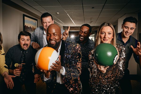 Group of friends laughing and holding bowling balls during a lively game at Pinstripes, promoting the Prime Time Play Unlimited Bowling Pass
