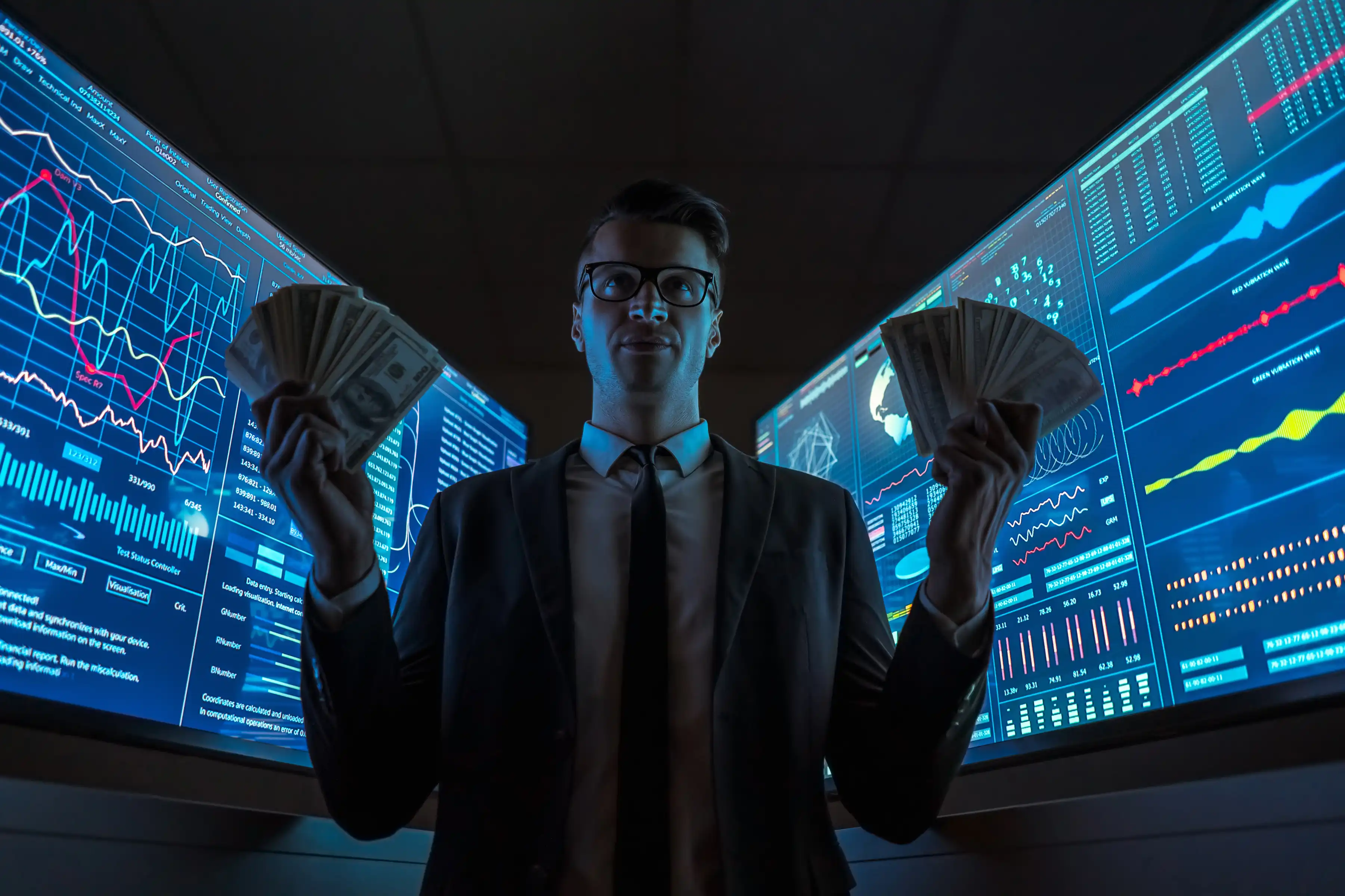 A man smiling and holding money in a room with data on screens