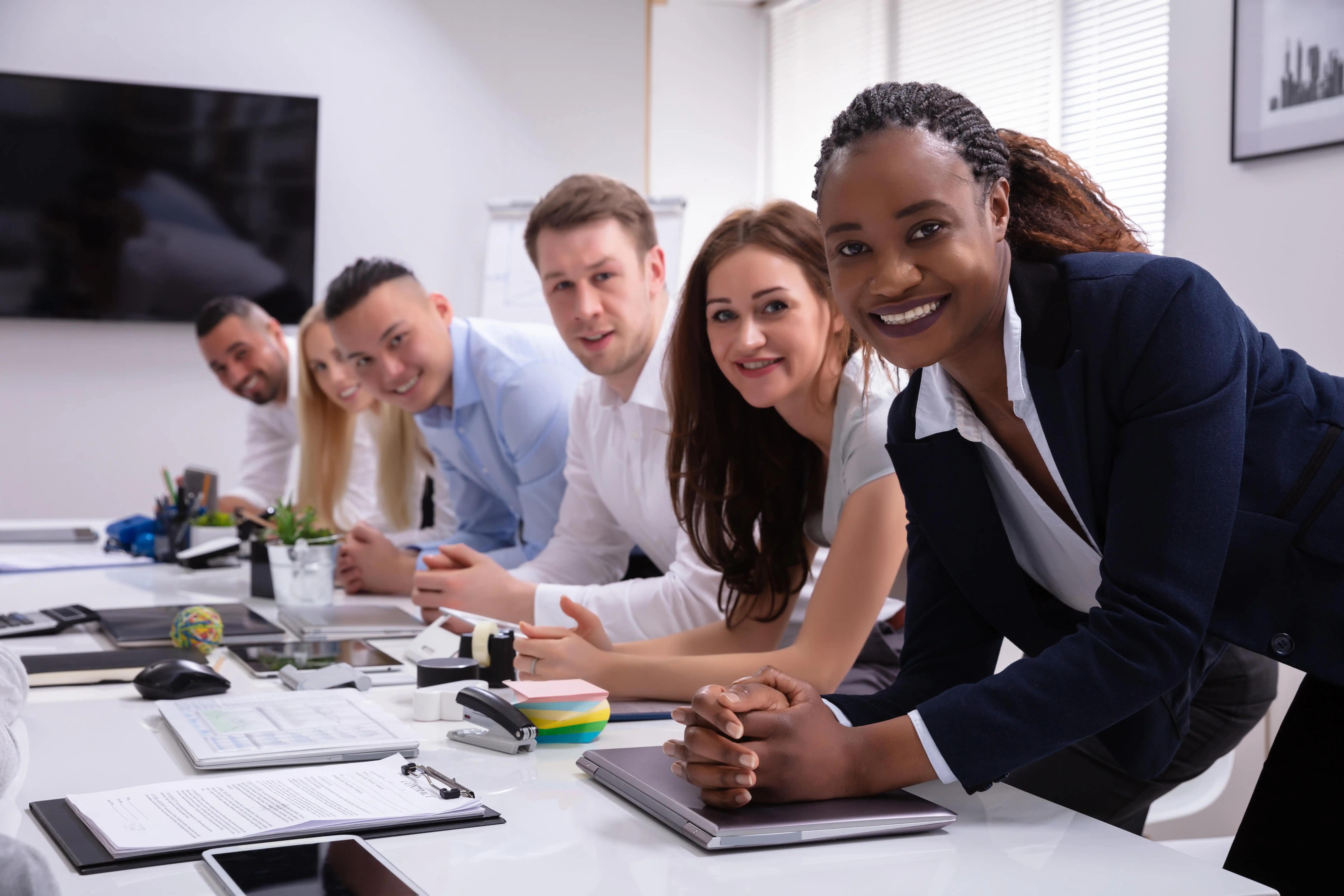 professional work colleagues leaning over a desk and smiling at camera