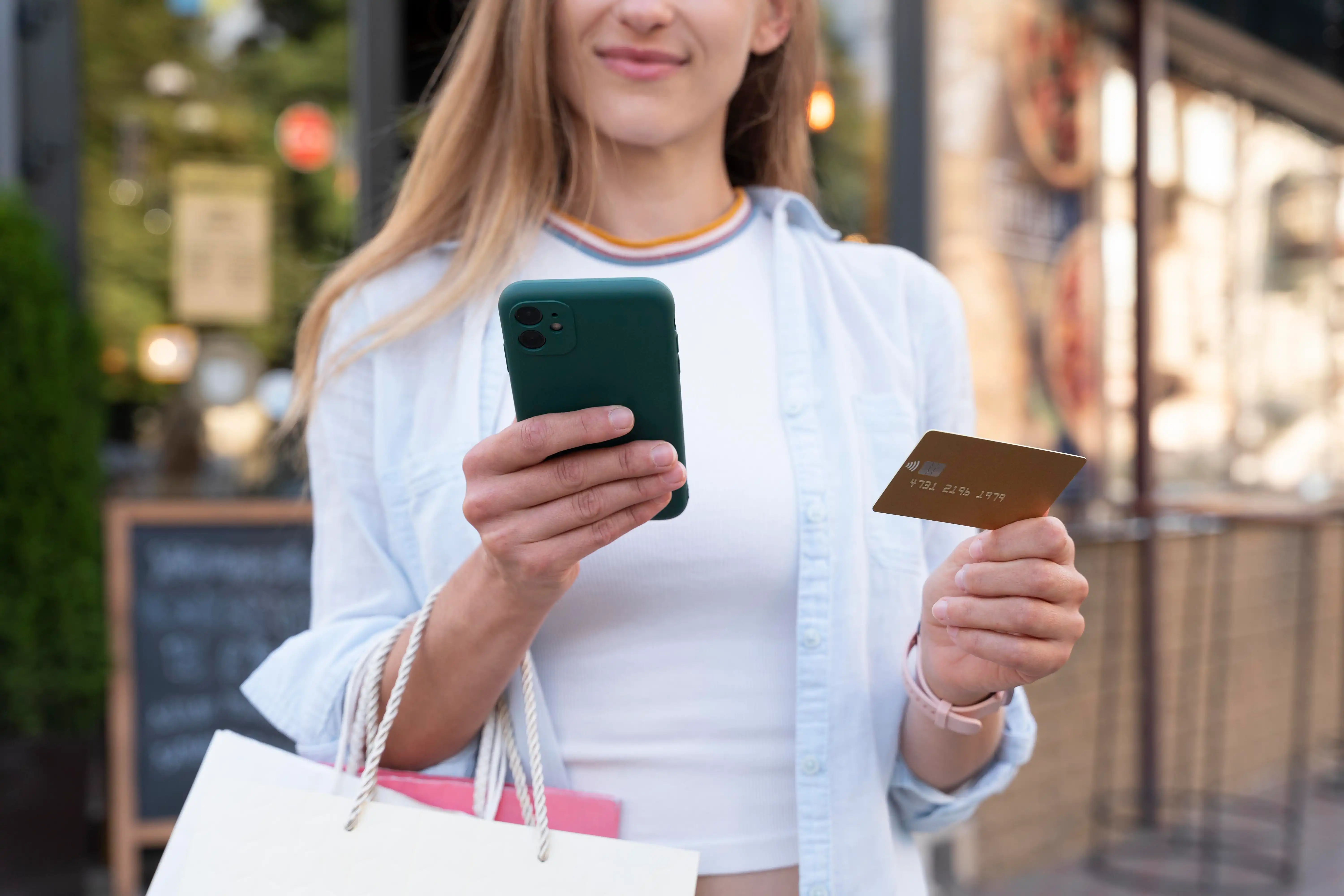 woman with shopping bags looking at phone in hand