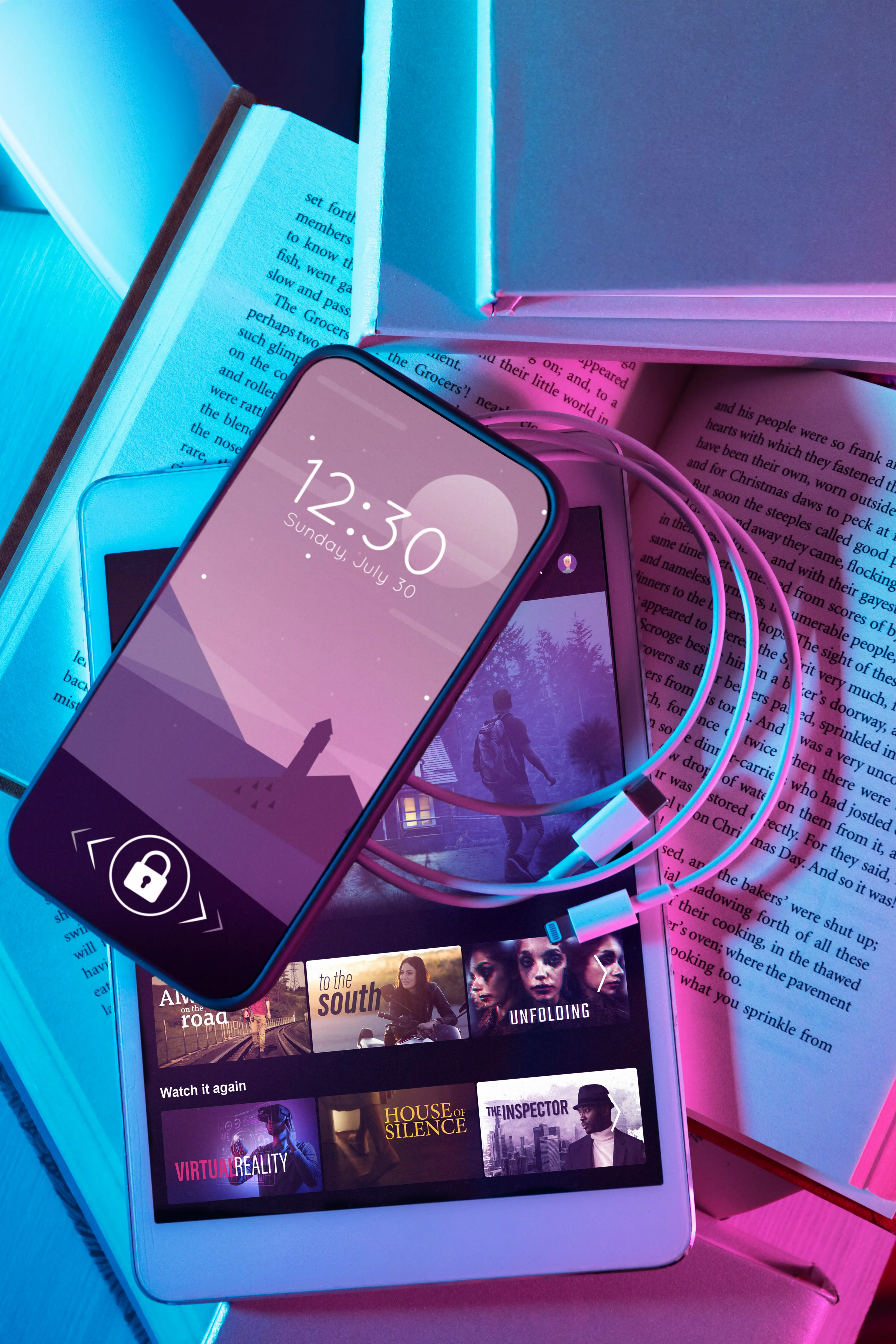 phone tablet and charger lying atop books
