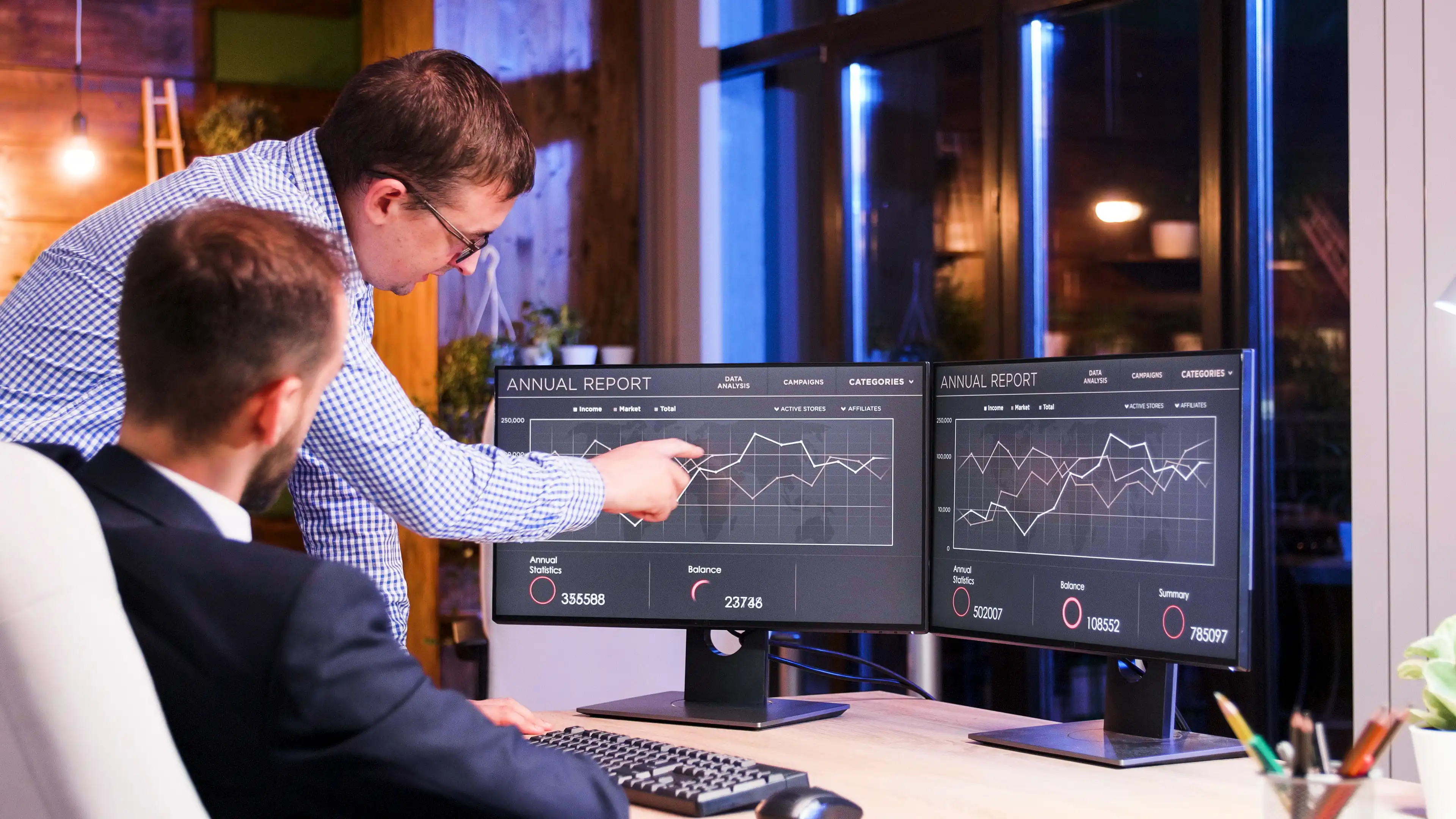Two employees looking at statistics on a screen