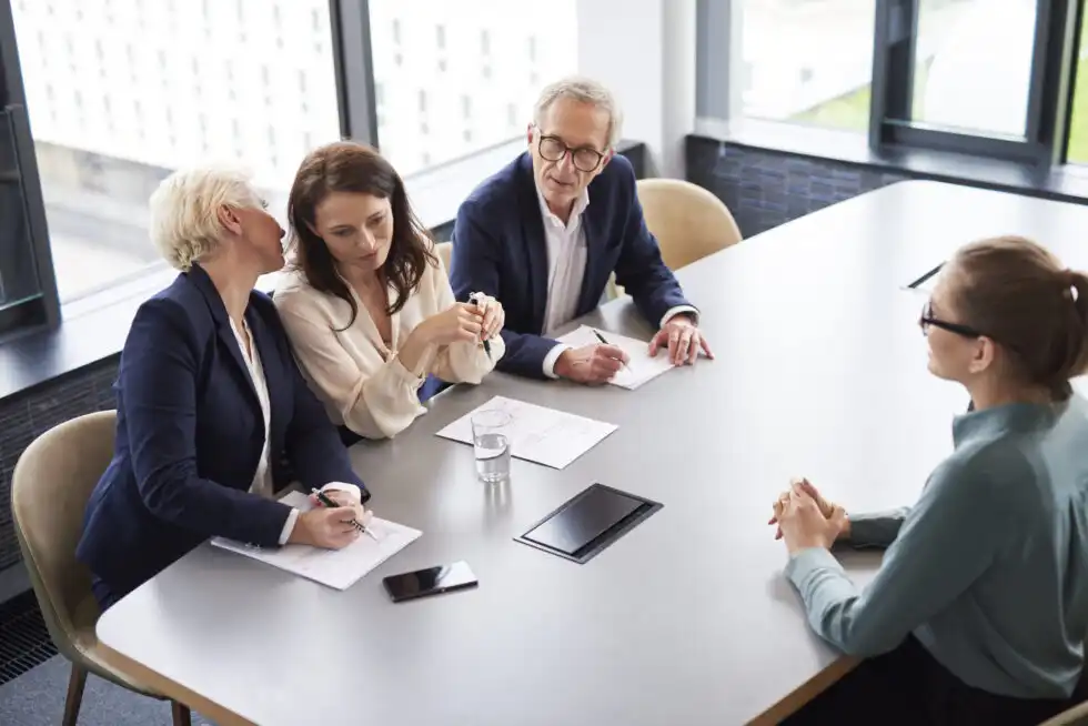 business people conversing at a table with papers on top
