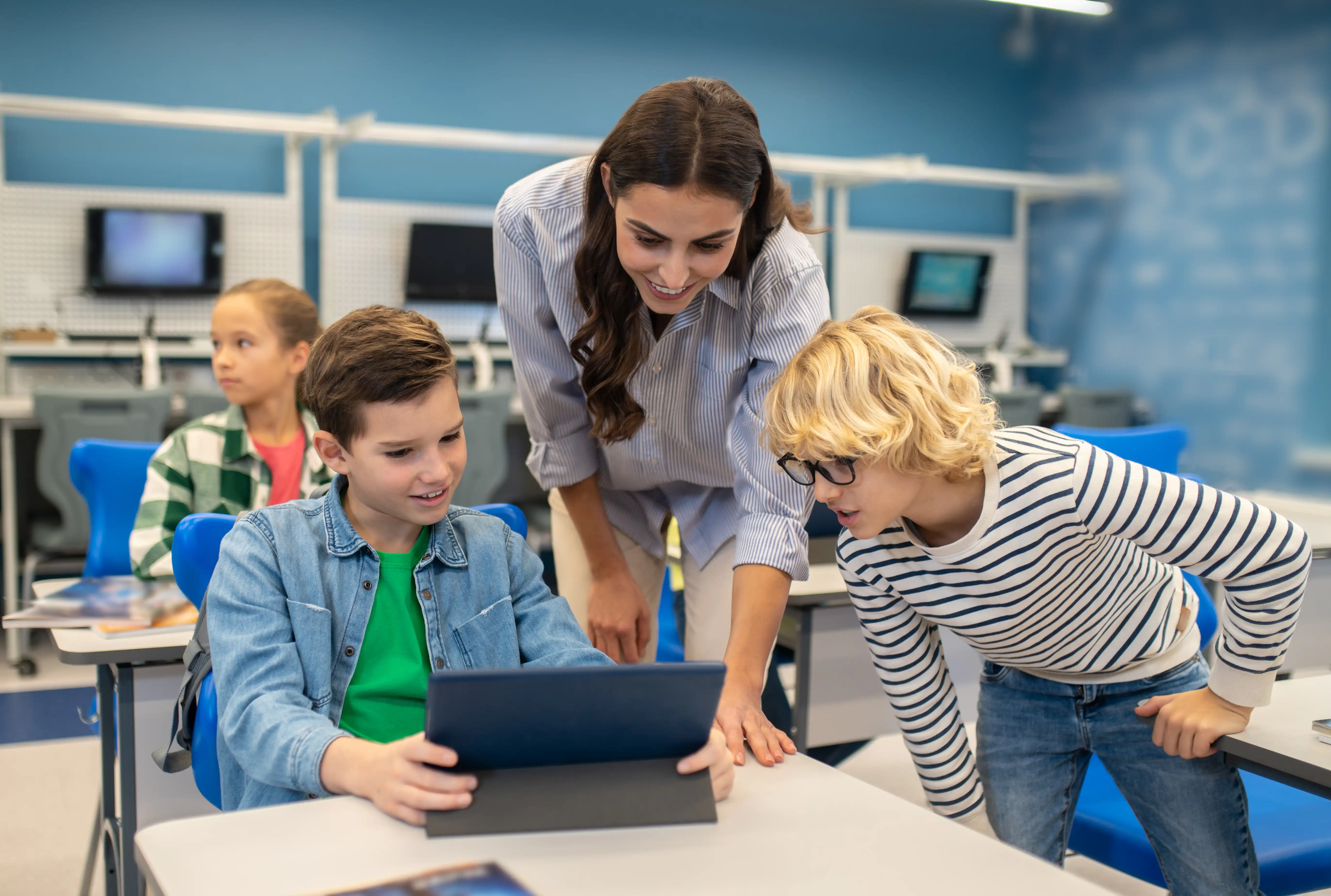 teacher helping young students using tablet