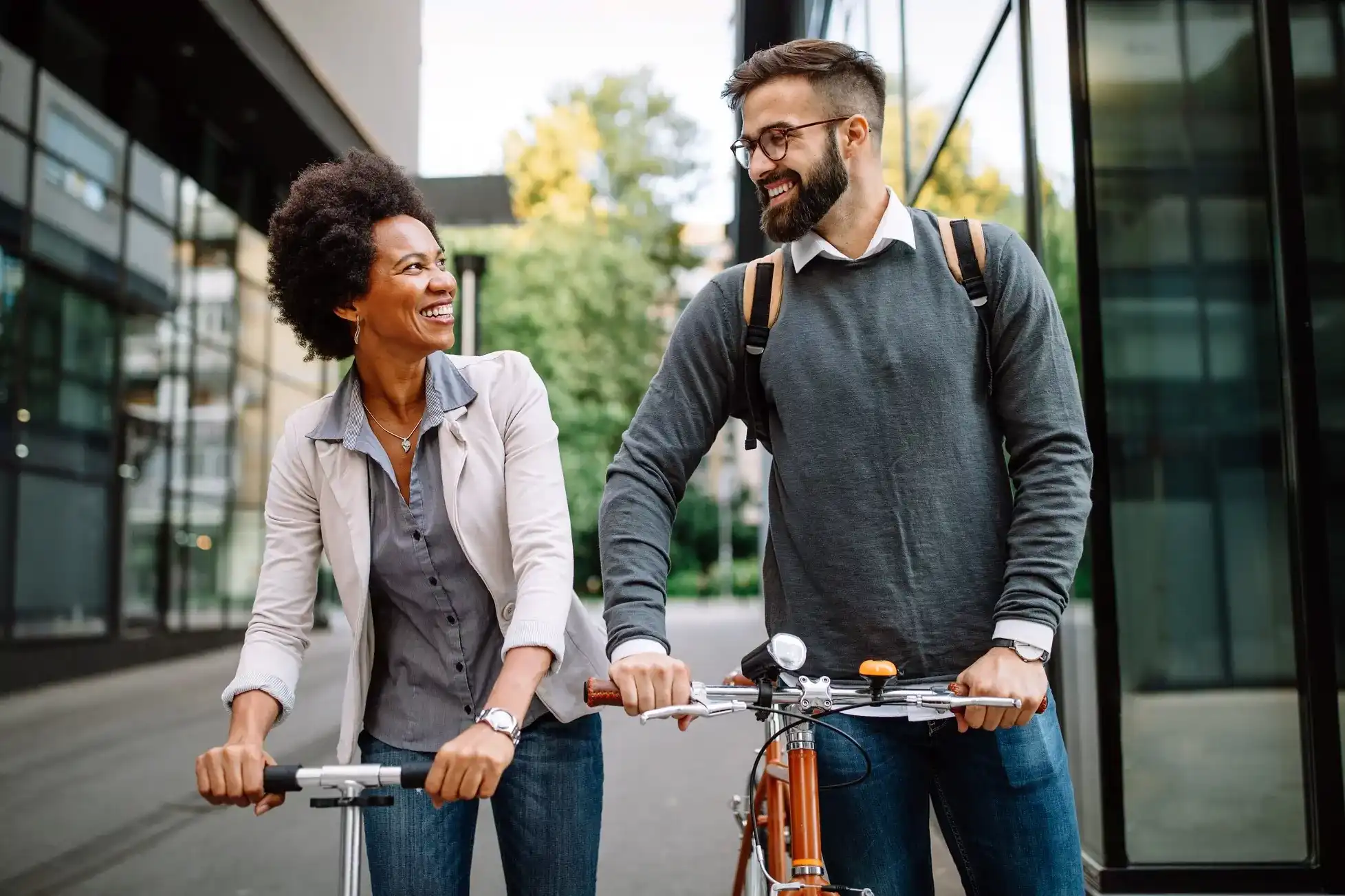 man and a woman walking together with their scooters in tow