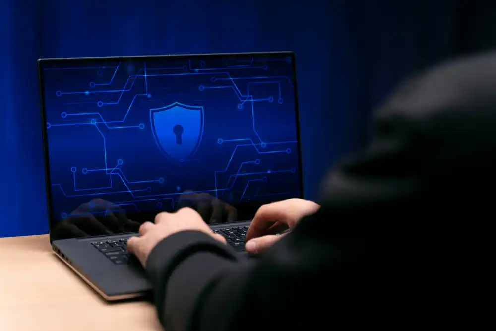 hands on laptop with shield icon on screen