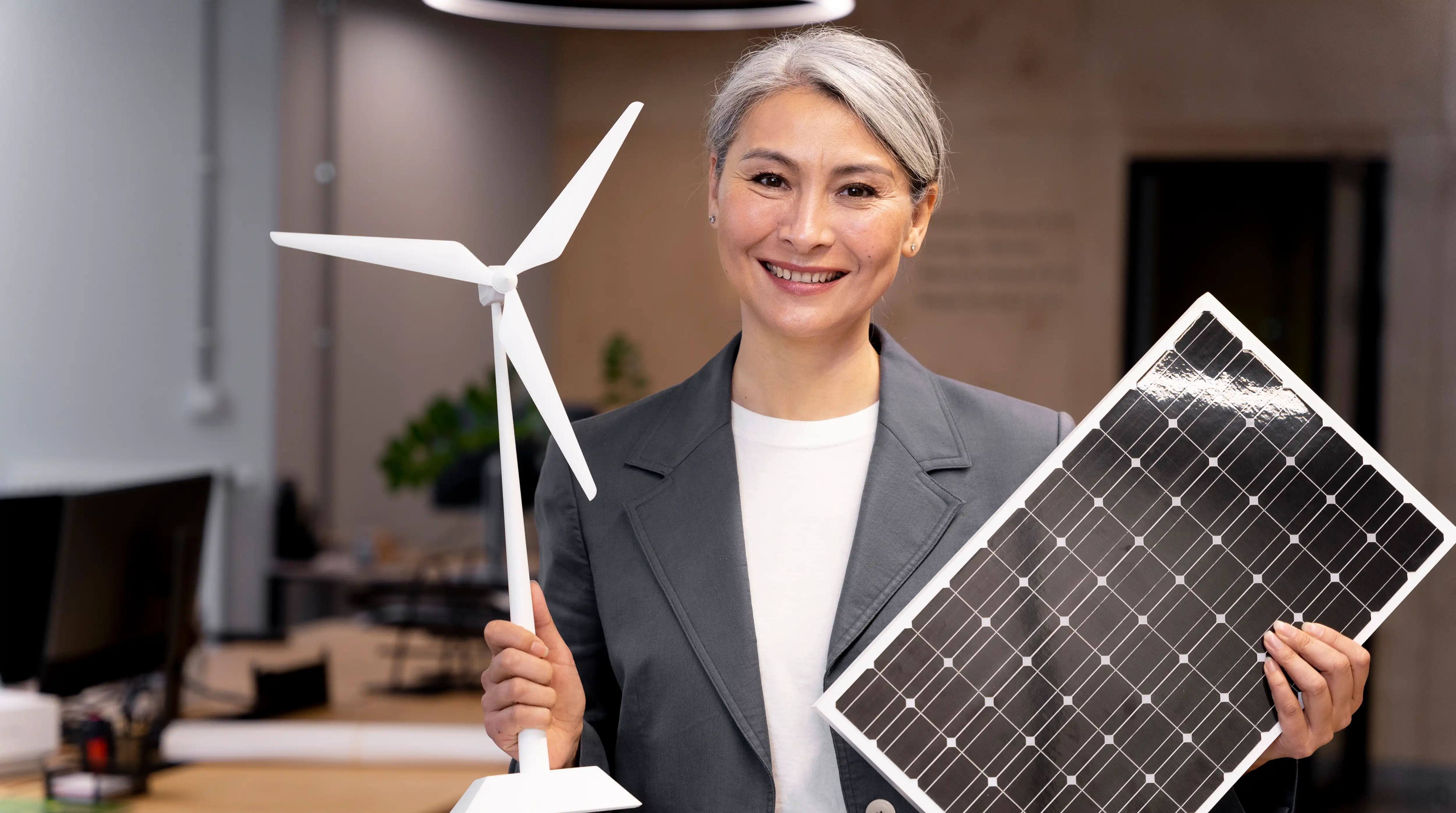 business professional holding solar panel and wind turbine model