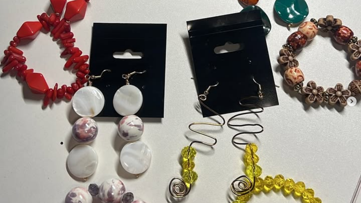 A flat lay of handmade beaded earrings and bracelets in coral, amber, teal, mother-of-pearl, and golden-yellow glass beads