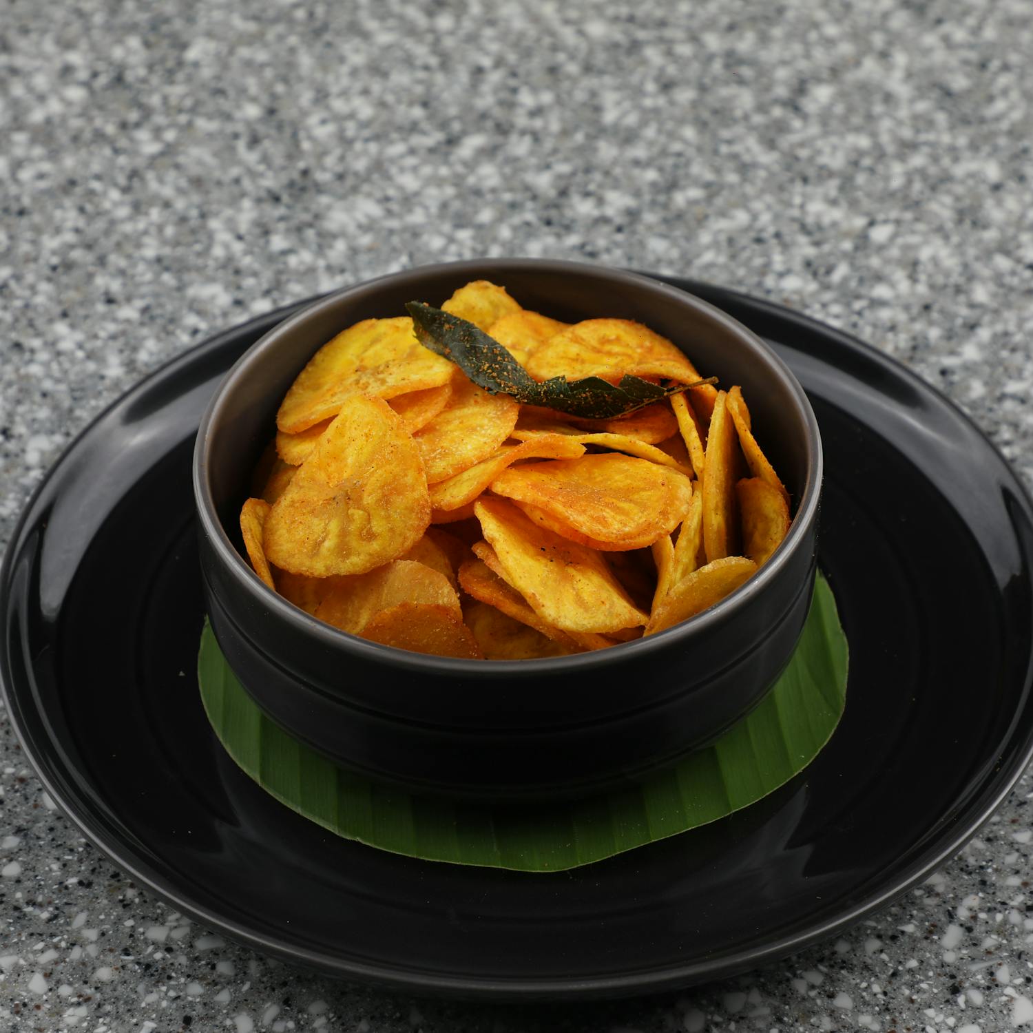 South Indian Malabar banana chips served in a traditional black bowl on a banana leaf