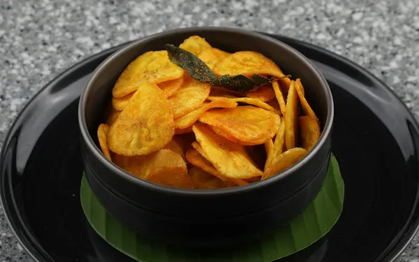 South Indian Malabar banana chips served in a traditional black bowl on a banana leaf