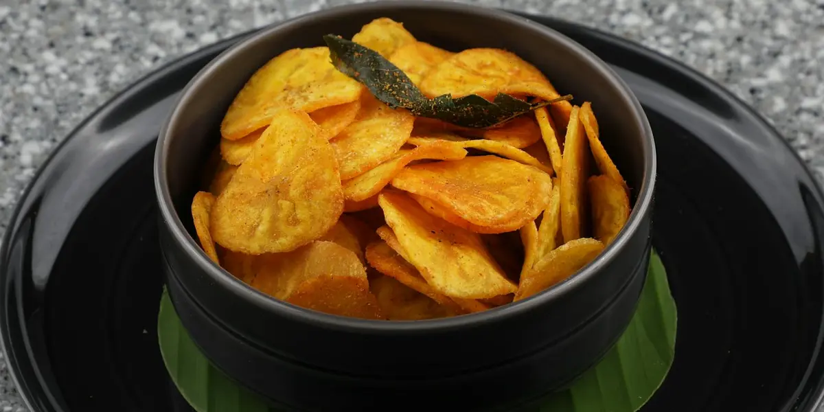 South Indian Malabar banana chips served in a traditional black bowl on a banana leaf