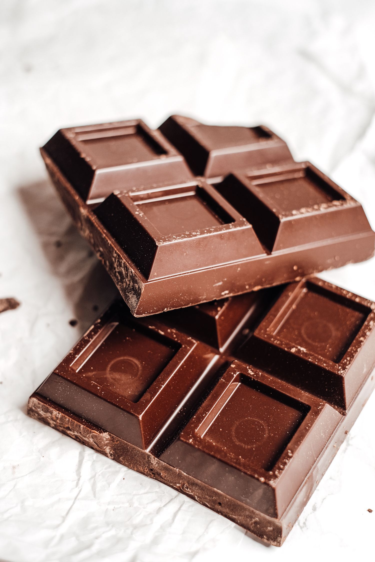 A stack of rich dark chocolate bars broken on parchment