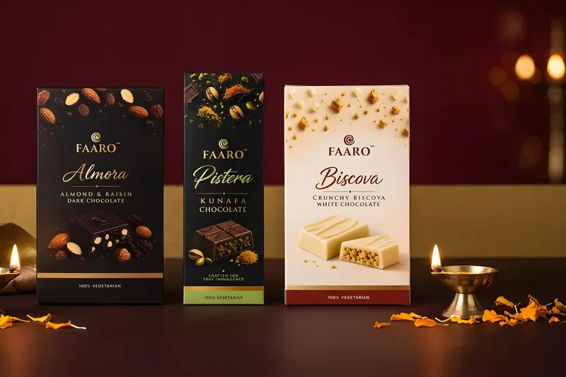 Three Faaro chocolate bars arranged for corporate Diwali gifting with brass diyas and marigold petals on a maroon and gold setting