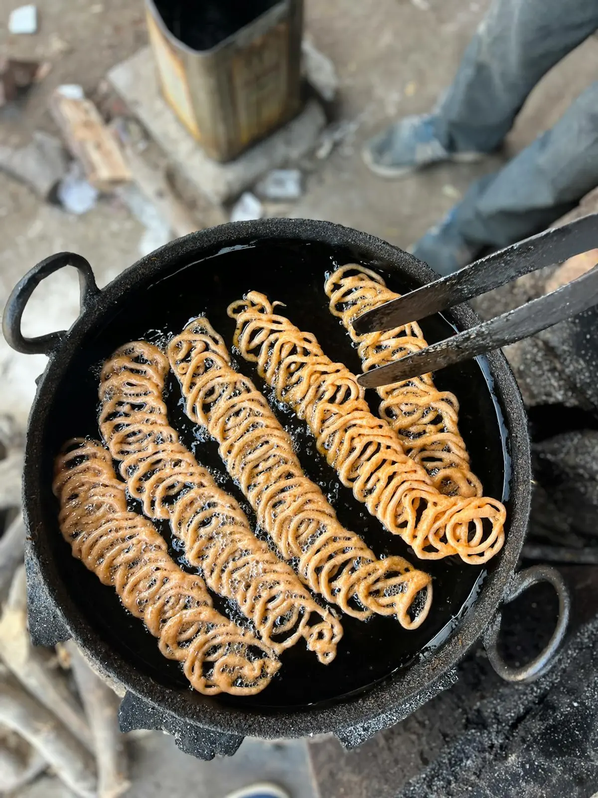 Traditional murukku being fried in hot coconut oil in a cast-iron kadai