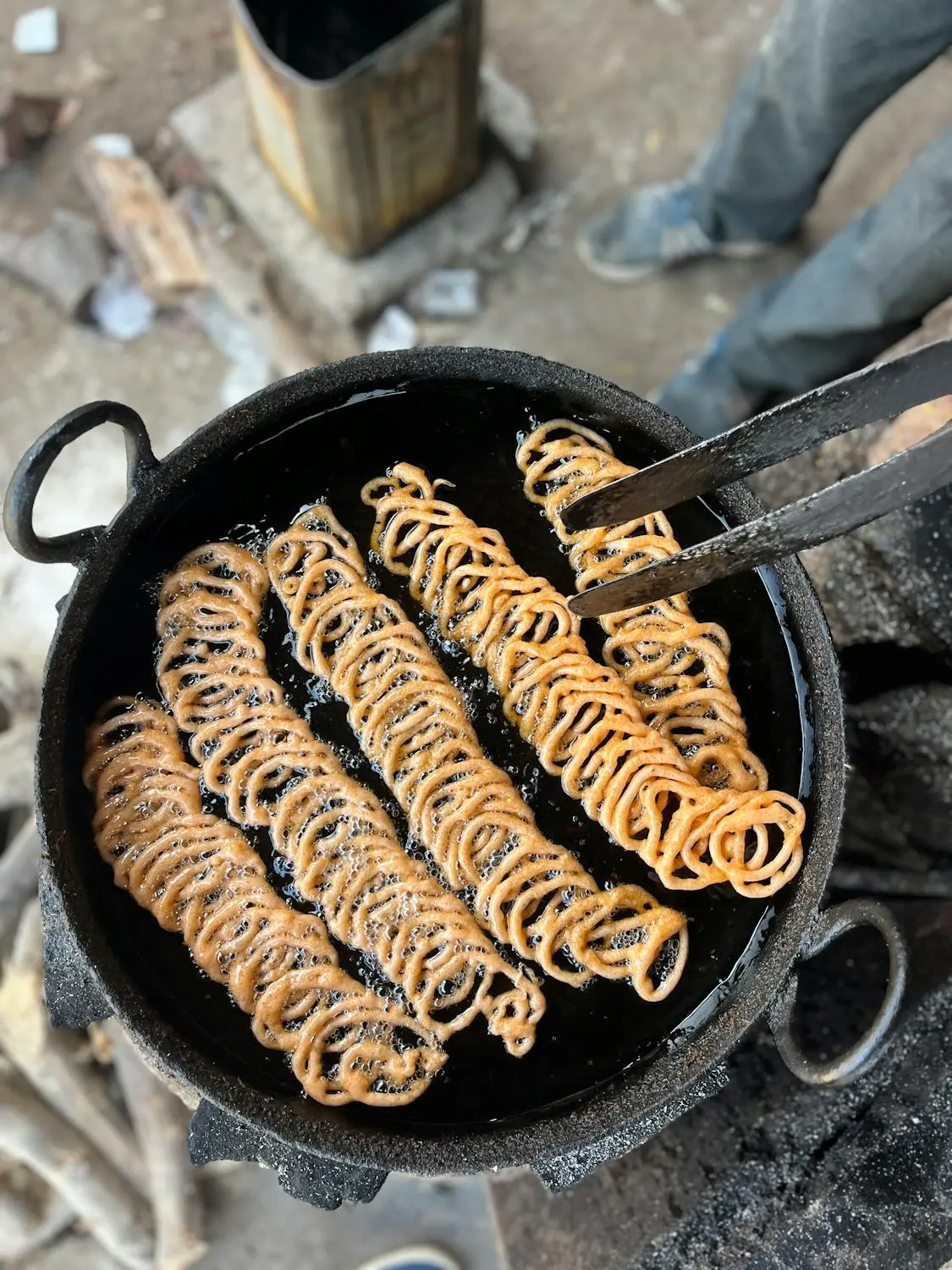 Traditional murukku being fried in hot coconut oil in a cast-iron kadai