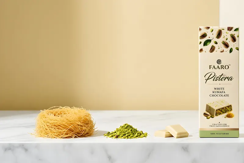 A row of Faaro white kunafa chocolate bars on a white marble ledge with kunafa strands and crushed pistachio