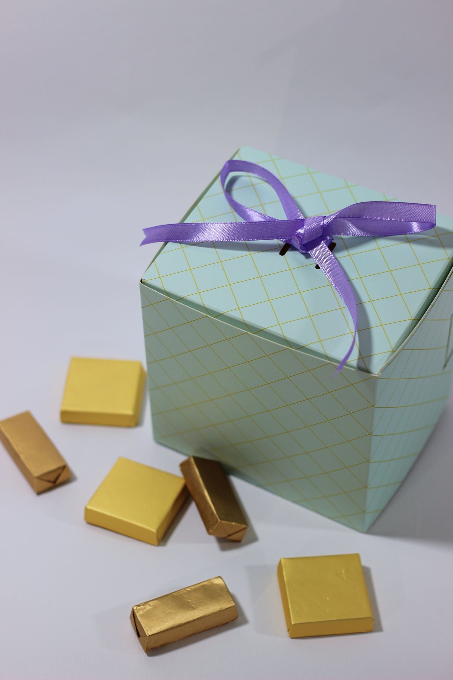 A premium chocolate gift box tied with ribbon alongside gold-wrapped chocolates