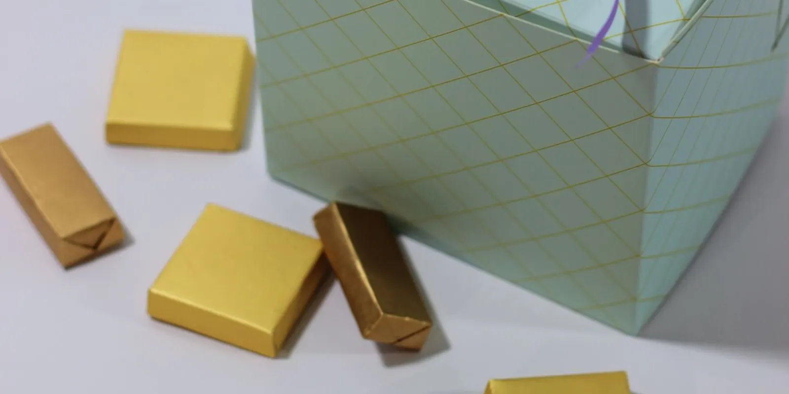 A premium chocolate gift box tied with ribbon alongside gold-wrapped chocolates