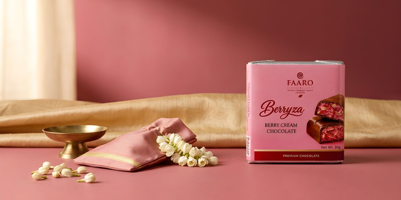 A Faaro Berryza berry cream chocolate pack on gold silk with a brass dish and jasmine, arranged as a South Indian wedding return gift