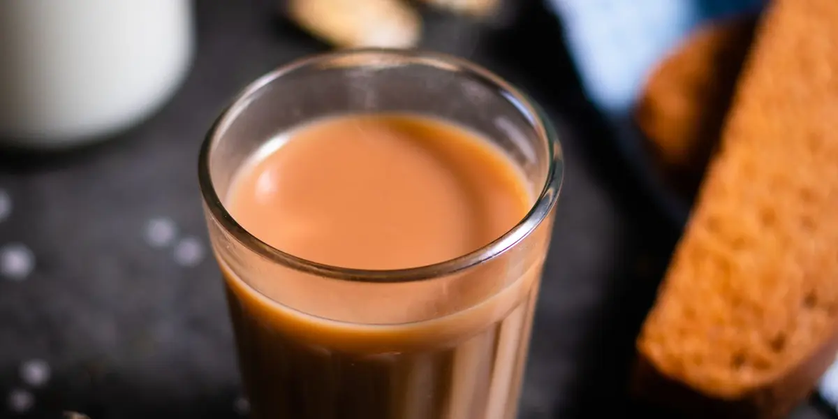 A glass of strong Indian masala chai beside crisp rusk — the classic tea-time snack pairing