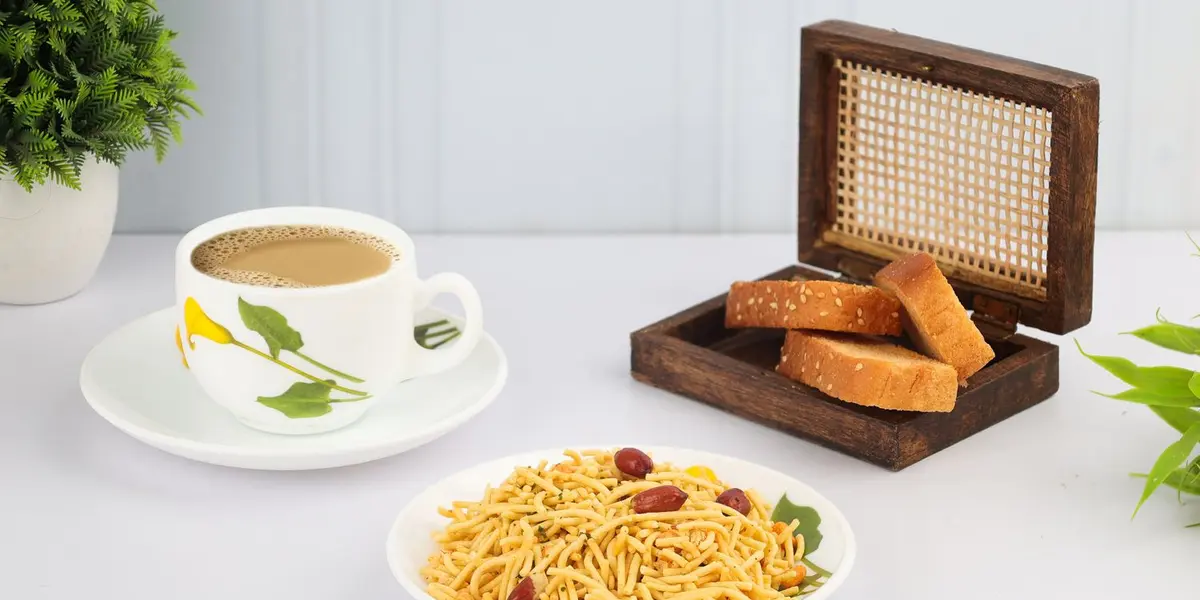 A plate of crunchy South Indian mixture (sev, peanuts and curry leaves) served with a cup of chai