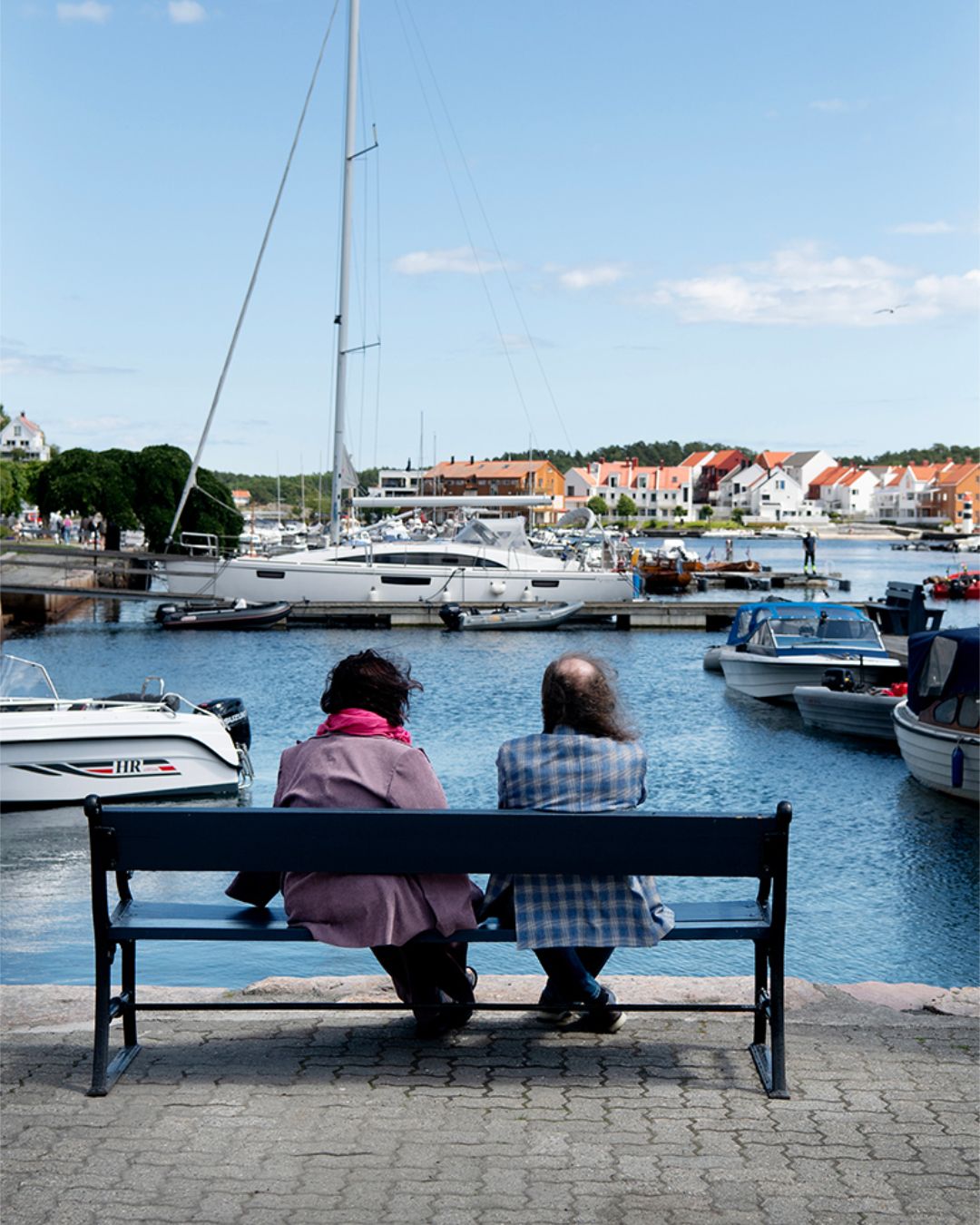 Et par sittende på brygga i Risør