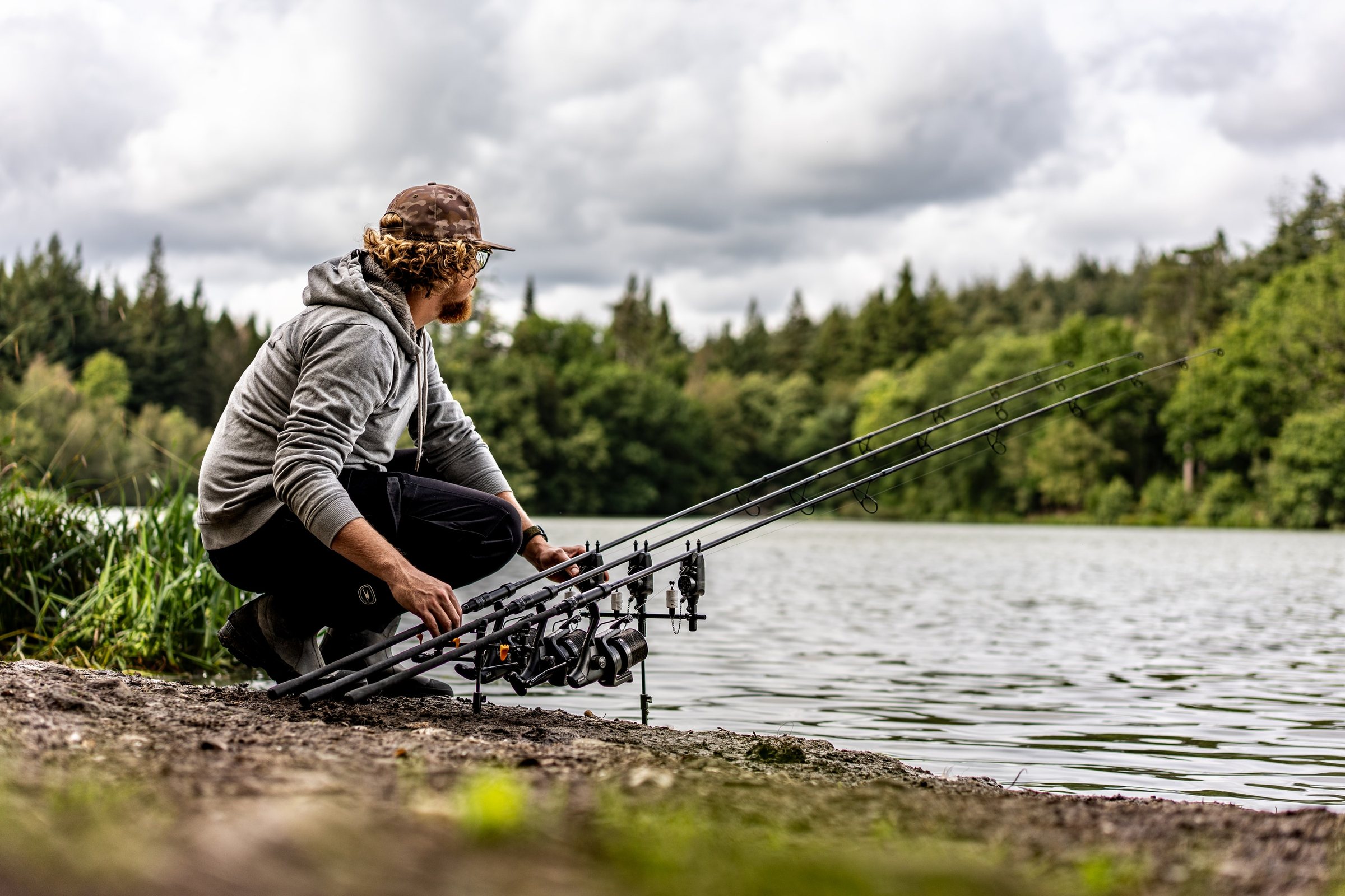 Joe crouched at the water's edge beside three rods pointing out over the lake
