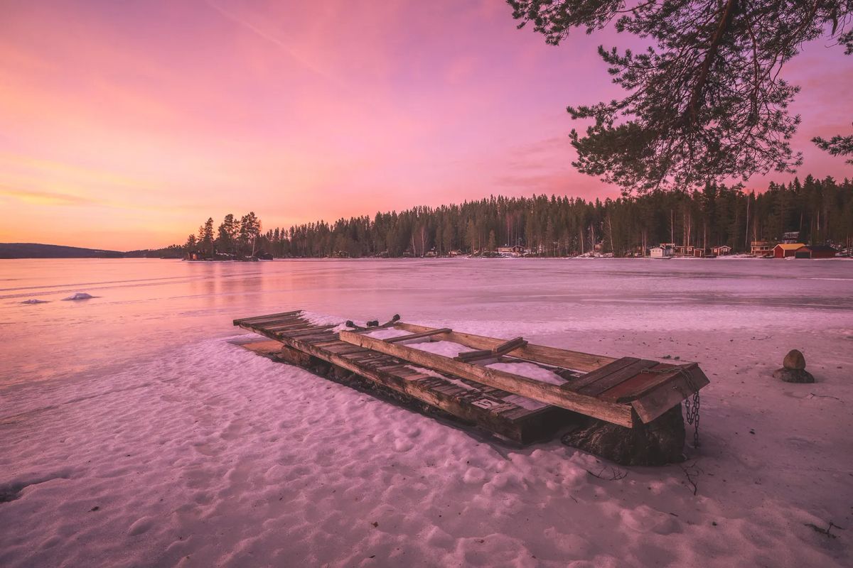 Brygga vid istäckt sjö i solnedgång vid Gimmen