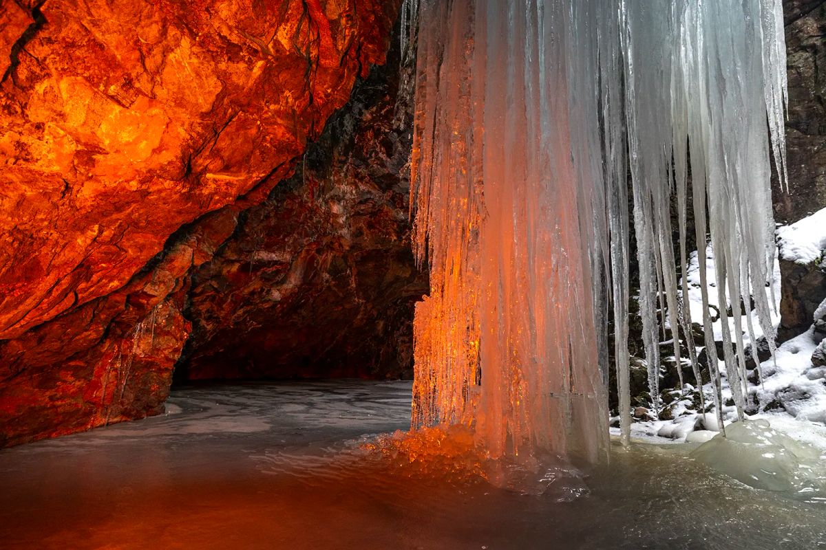 Orange LED-ljus på långa istappar i grotta