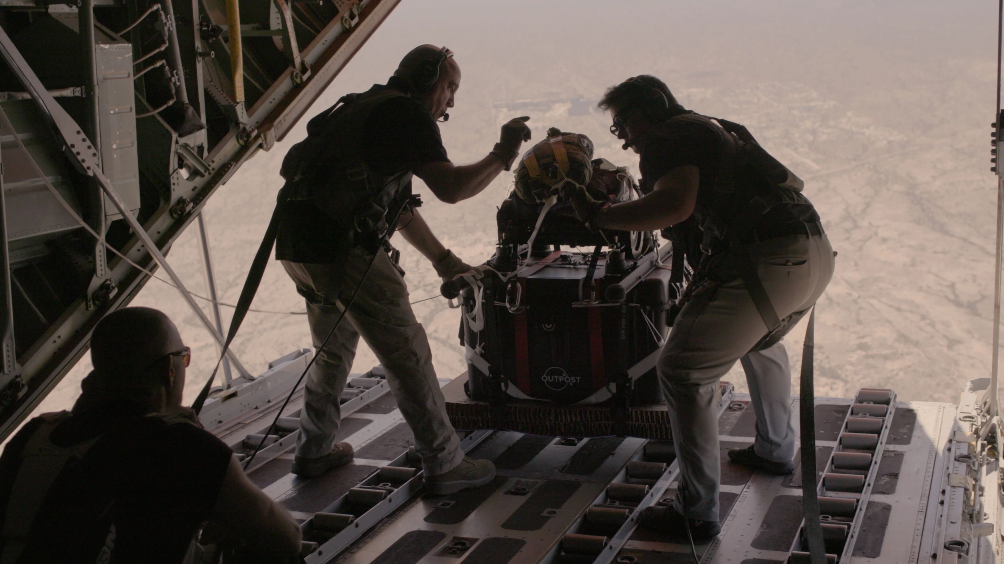 Flight crew pushing an Outpost AirDrop 200 out of a C-130
