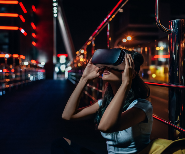 Femme regardant dans un casque de réalité virtuelle dans une rue éclairée