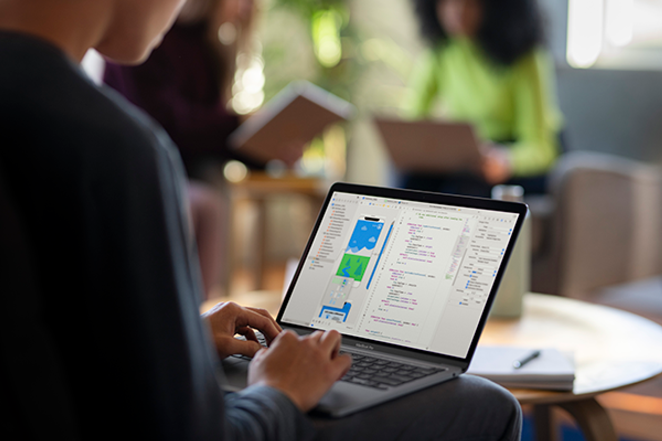 Une personne assise qui utilise son ordinateur portable Apple.