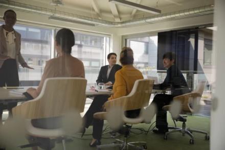 Salle de réunion avec 5 personnes dont 4 assises