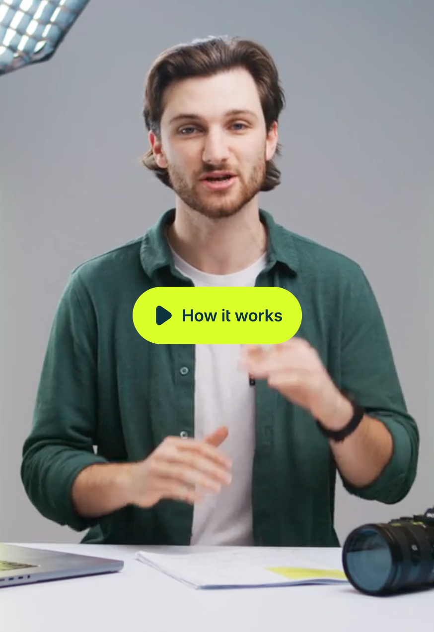 A man in a green shirt talking to camera, mid-gesture, in a softly lit room