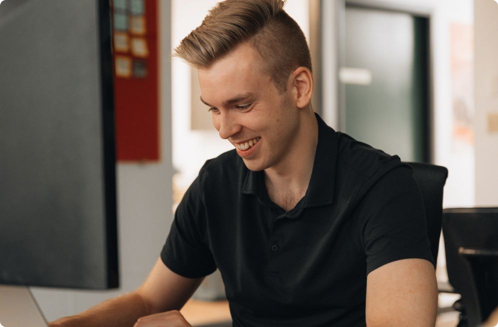 A Setsail team member smiling as he works at his laptop in the Vancouver office
