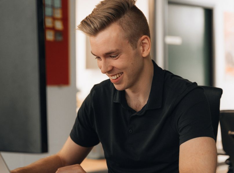 A Setsail team member smiling as he works at his laptop in the Vancouver office