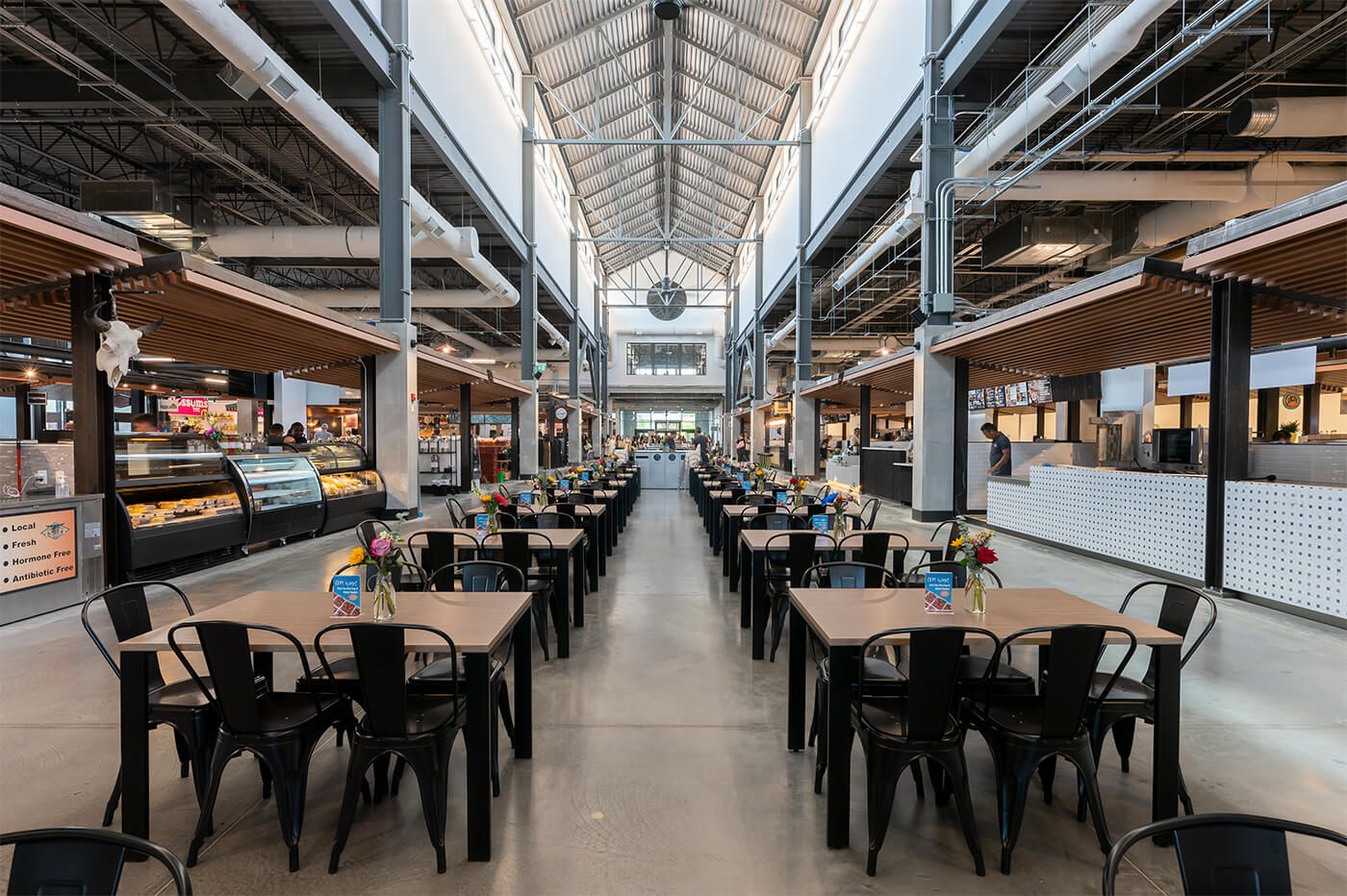 A Calgary market hall: rows of tables between food stalls under a high glass roof