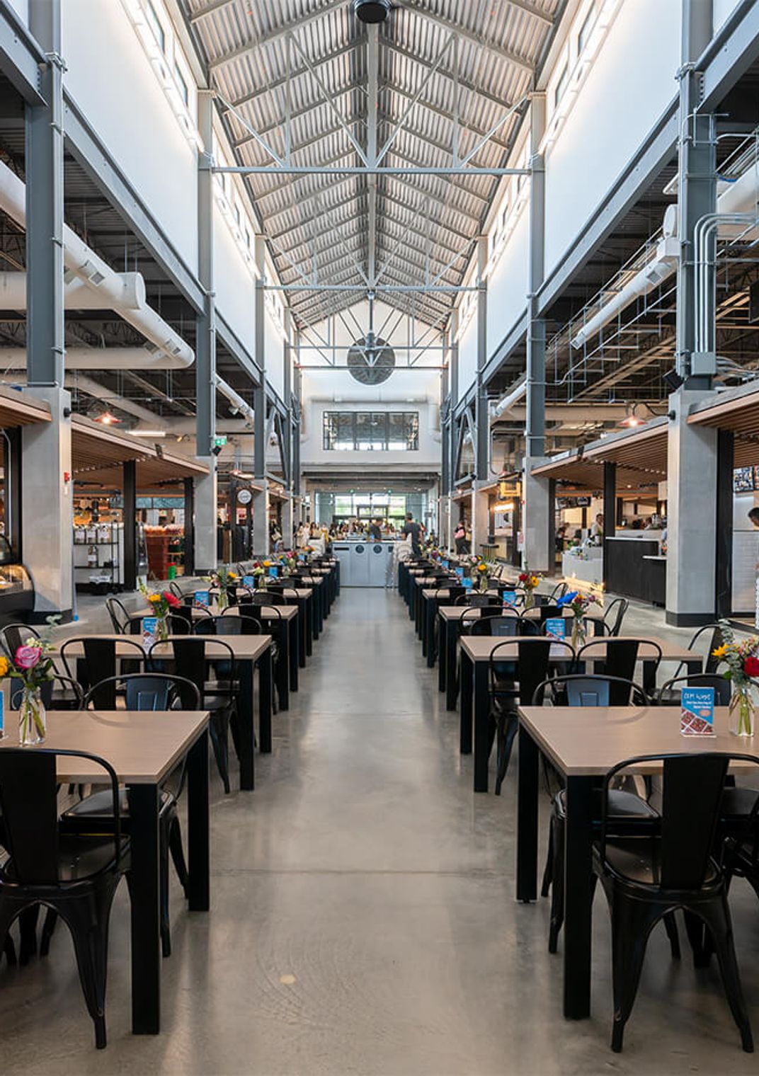 A Calgary market hall: rows of tables between food stalls under a high glass roof