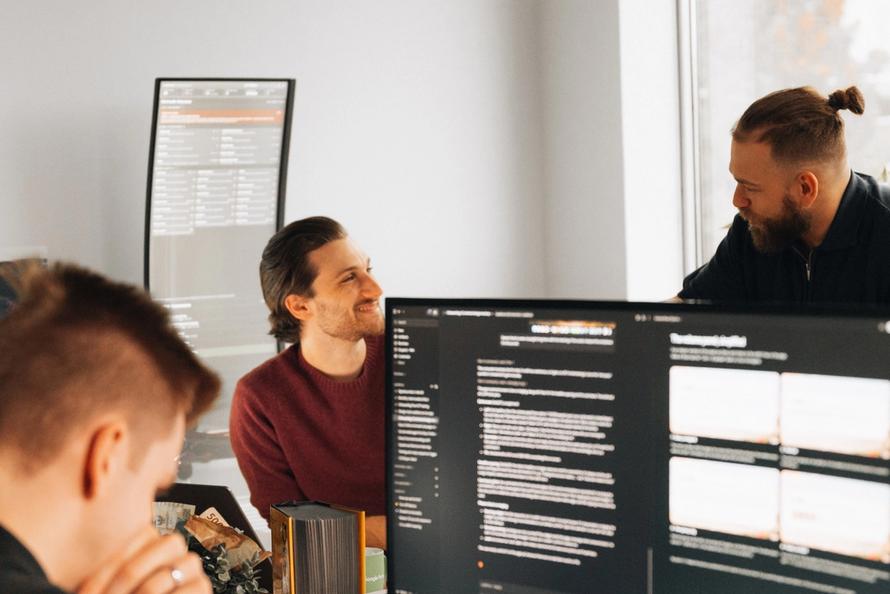 Setsail team members at their desks in the Vancouver office, one standing to talk over a monitor of campaign notes