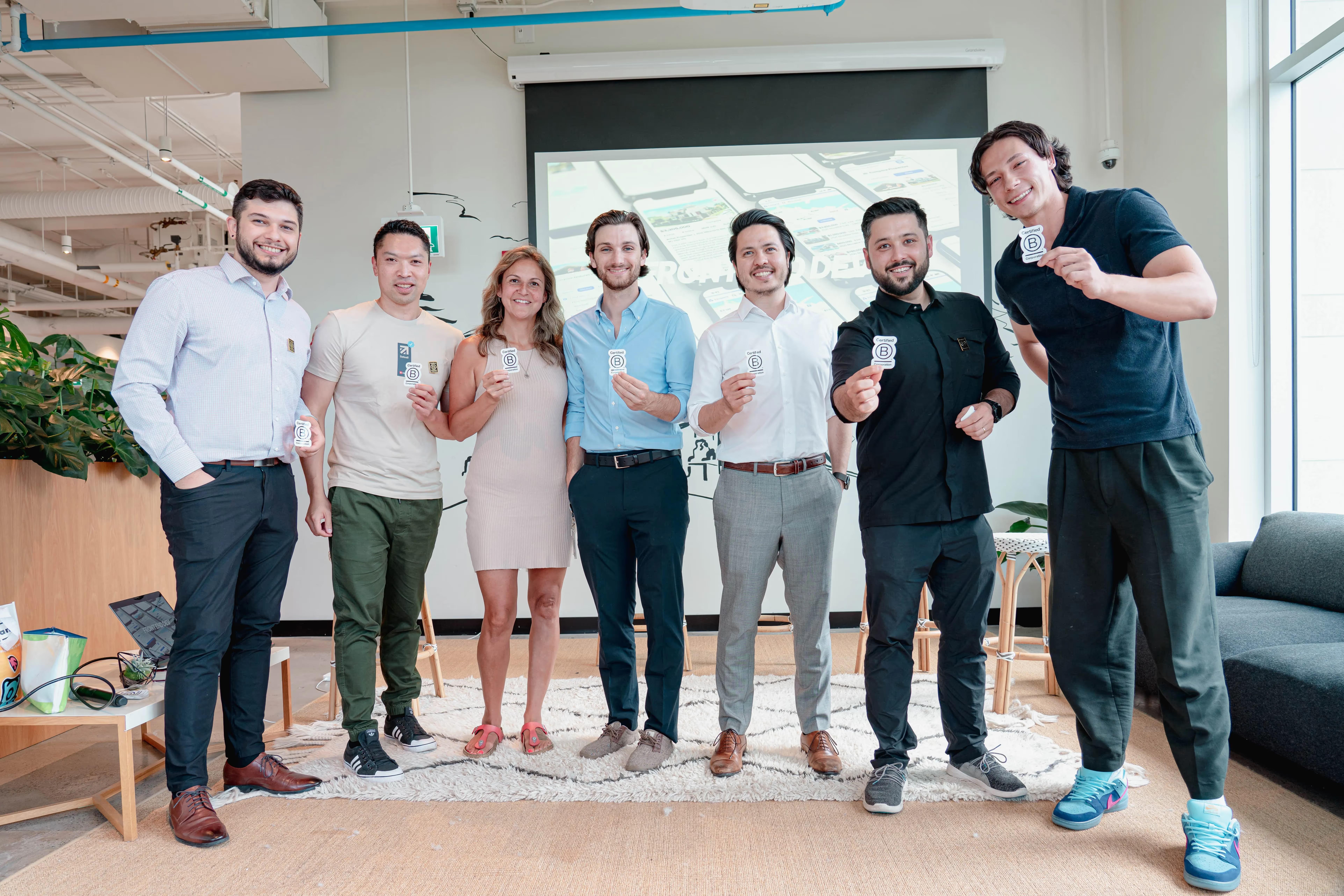 Seven Setsail Marketing team members raising drinks in the office at the B Corp certification happy hour