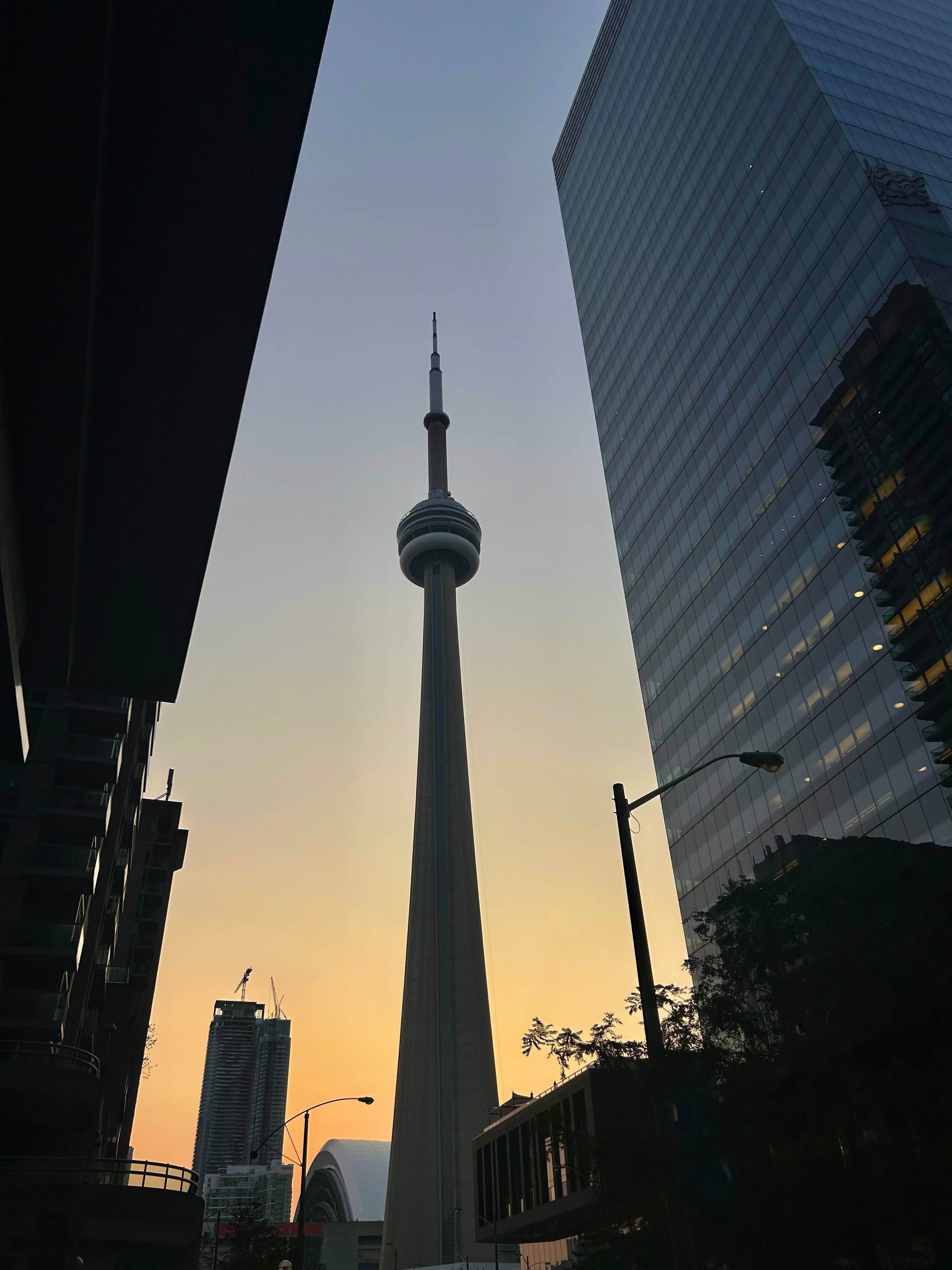 The CN Tower at dusk between downtown Toronto towers