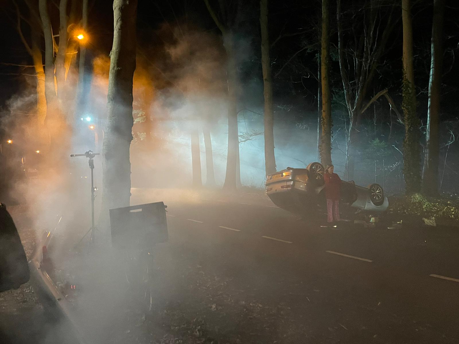 Een auto die op de kop ligt met daarrond een mist