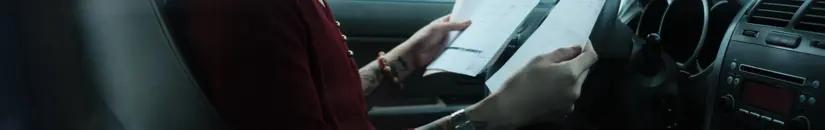 Frau in einem Auto mit Papierblättern 