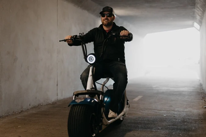 Man with electric scooter riding through tunnel