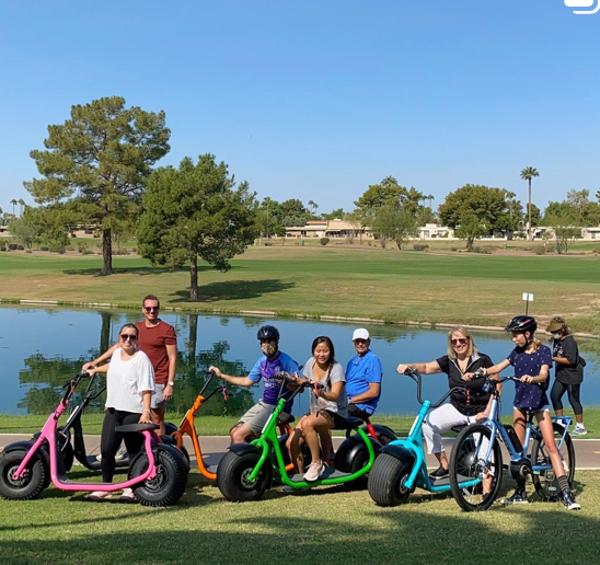 Group photo with people on bikes and scooters at lake