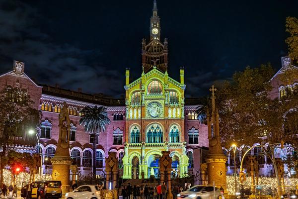 The ornate Modernista pavilions of Hospital de Sant Pau in Barcelona, with ceramic domes and sculpted facades set in peaceful gardens under a clear blue sky